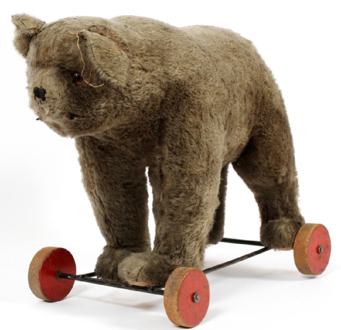 STEIFF MOHAIR BEAR ON WHEELS C1930: STEIFF, MOHAIR BEAR ON WHEELS, C1930, H 13 1/2", L 19" Having light brown color mohair, button on ear, growl draw string, wood wheels on platform.