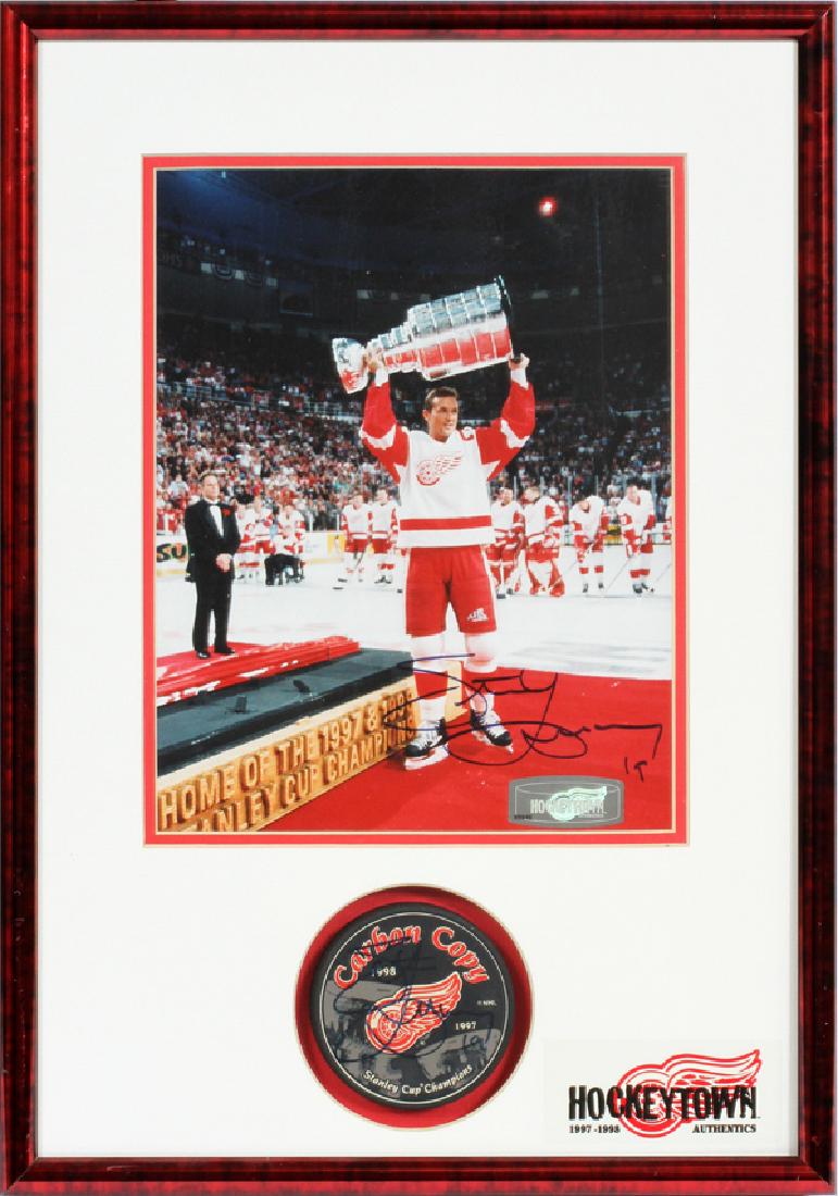 RED WINGS STEVE YZERMAN SIGNED PHOTO & PUCK: DETROIT RED WINGS STEVE YZERMAN SIGNED PHOTO & HOCKEY PUCK, H 17 1/2", W 12":A framed Detroit Red Wings photograph and hockey puck signed by Steve Yzerman, with certificate of authenticity signed by A
