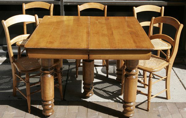AMERICAN MAPLE DINING TABLE & SET OF CHAIRS: AMERICAN MAPLE DINING TABLE & SET OF SIX CHAIRS, LATE 19TH CENTURY:Including table resting on five cylindrical legs plus one center support and chairs with cane seats. Castors on legs of table, also i