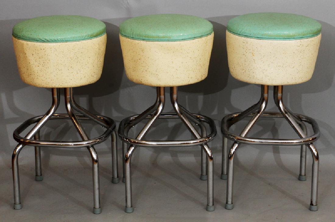 MID-CENTURY MODERN CHROMED METAL BAR STOOLS: MID-CENTURY MODERN CHROMED METAL AND FAUX LEATHER BAR STOOLS, THREE, H 28.25" :Three bar stools having chromed metal legs and faux leather seats in pale green and ivory.