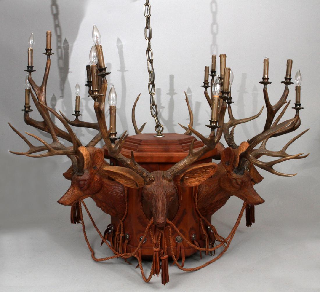 CARVED WOOD DEER HEADS AND LEATHER CHANDELIER: MANSION SIZE CARVED WOOD DEER HEADS AND LEATHER CHANDELIER, H 41", DIA 56" :Six carved bucks with horns fitted with three lights each that surround a leather clad center. Eighteen lights. From a Lone