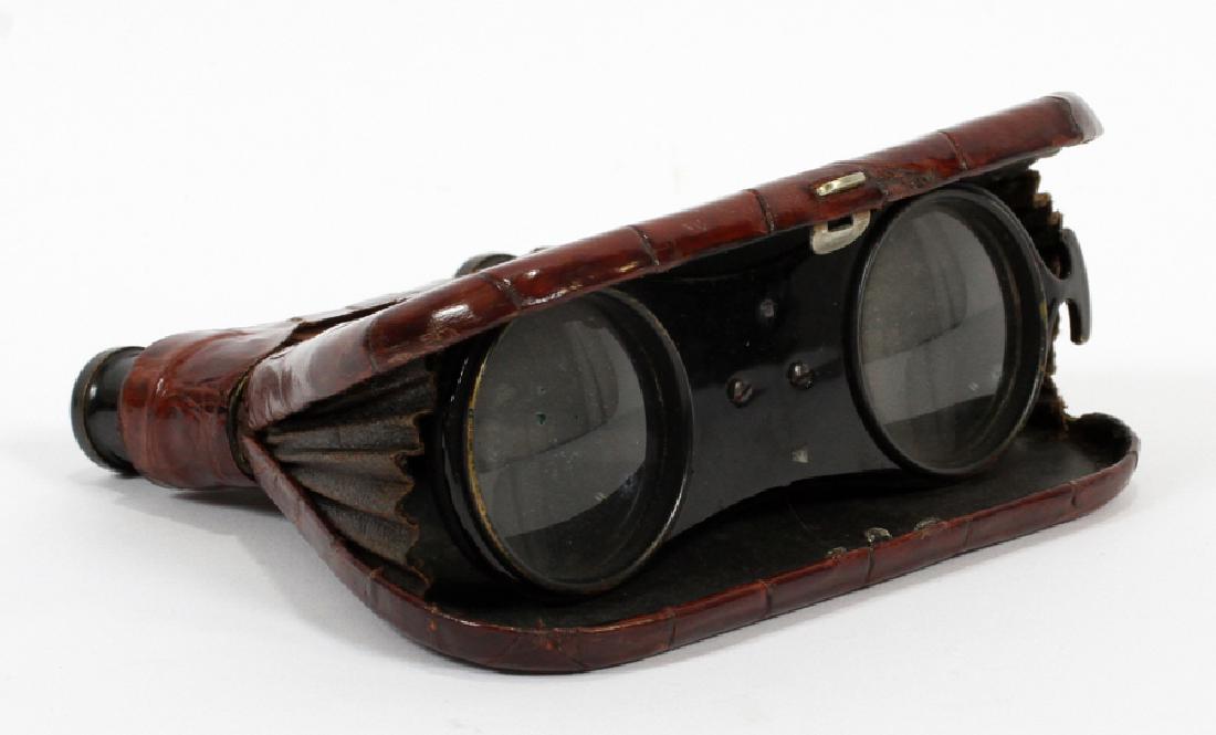 PURSE STYLE OPERA GLASSES, H 4", L 4.5": PURSE STYLE OPERA GLASSES, H 4", L 4.5":An antique purse style opera glasses. Encased in a metal and alligator leather case. Front lenses fold up into the front of its case.