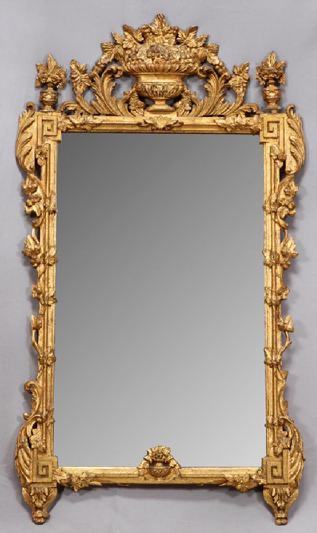 GILT WOOD MIRROR, H 56", L 31": GILT WOOD MIRROR, H 56", L 31"An elegant gilt wood mirror. This piece features Greek key motifs to the corners, scroll forms and four blooming urns to the horizontal panels.