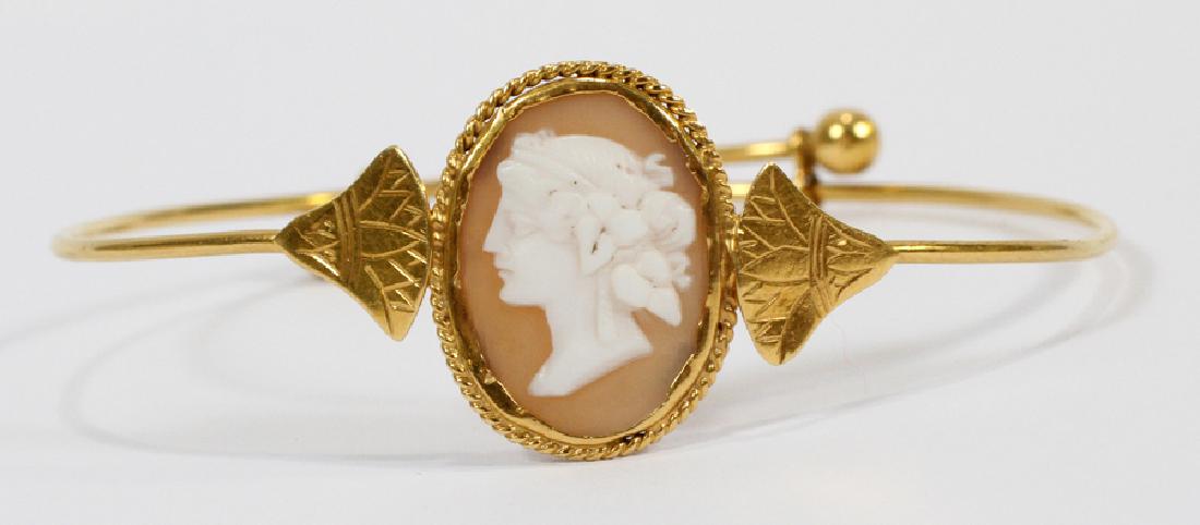 GOLD, SHELL CAMEO BANGLE BRACELET DIA 2.5" TO 3": GOLD, SHELL CAMEO BANGLE BRACELET DIA 2.5" TO 3" Gold and cameo bracelet. Having a central carved shell cameo depicting a woman's head in profile flanked by lotus leaves. Adjustable wire form with gol