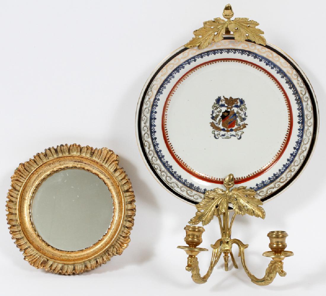 PORCELAIN AND GILT METAL WALL SCONCE: PORCELAIN AND GILT METAL WALL SCONCE, H 15'', W 10'', D 6'' Brass two-arm sconce with a porcelain plate with heraldry. Plate is marked "Kaiser, North Carolina". Circle shaped mirror framed in a shell 