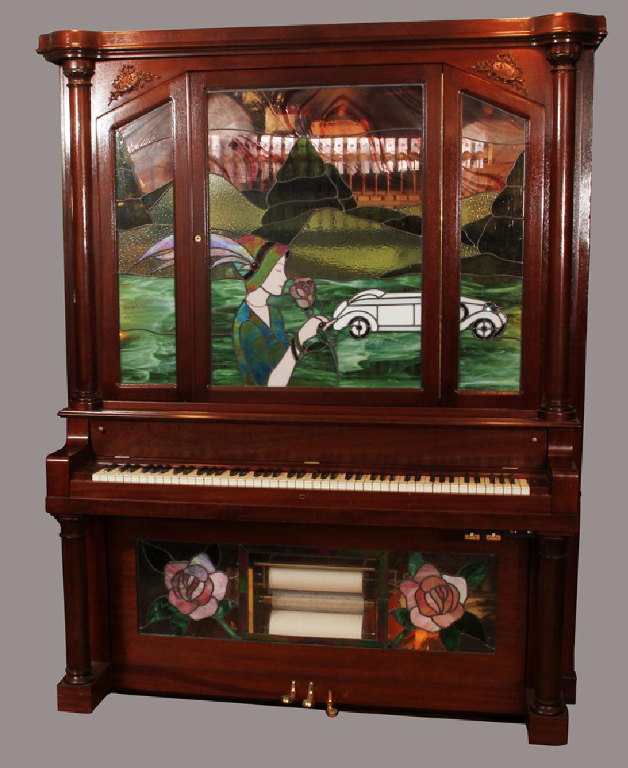 CLARENDON HADEROFF MAHOGANY PIANO/NICKELODEON: CLARENDON HADEROFF PIANO CO., CARVED MAHOGANY UPRIGHT PIANO/NICKELODEON, C. 1911, H 78", L 60", D 27", INSET WITH FIGURAL LEADED GLASS :The 3 panel leaded glass depicts a woman wearing a hat with long