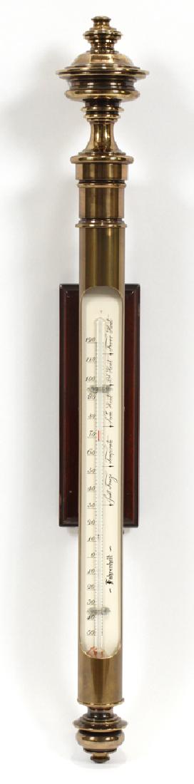 ENGLISH BRASS & MAHOGANY, WALL MOUNT THERMOMETER: ENGLISH BRASS & MAHOGANY, WALL MOUNT THERMOMETER, H 32.5", L 4", D 4" :A modern English brass wall mount thermometer. Having a mahogany mount. From the Estate of Wallace D.Riley, Grosse Pointe Farms.