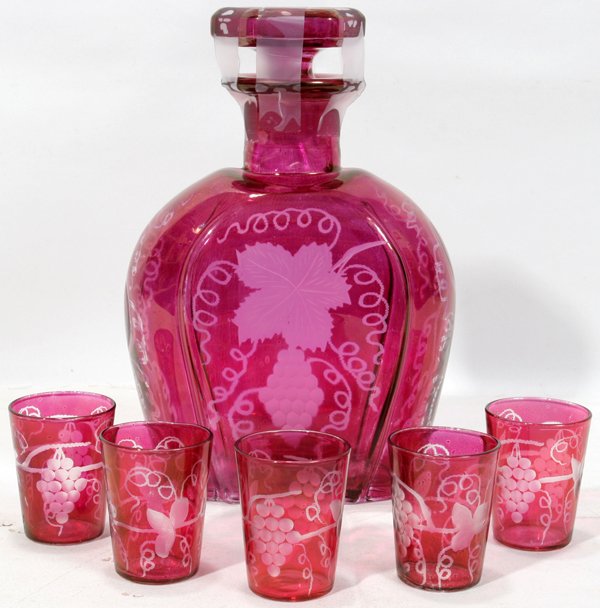 ETCHED CRANBERRY GLASS DECANTER & GLASSES: ETCHED CRANBERRY GLASS DECANTER & GLASSES, H 2 1/4" & 8 1/4":Including 1 decanter (H 8 1/4", W 6") and 5 matching glasses (H 2 1/4", Dia 1 5/8") all of an iridescent cranberry glass that is etched wit