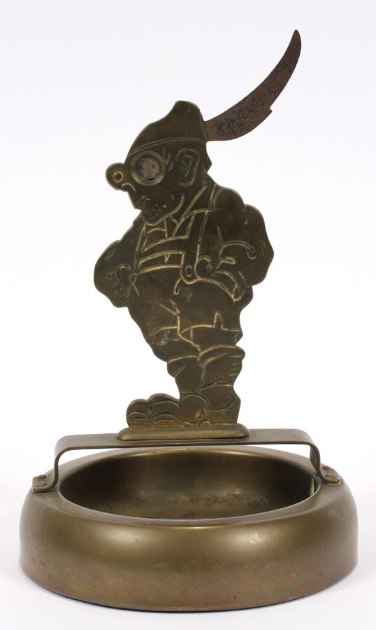 BAVARIAN, FIGURAL, BRASS CIGAR CUTTER AND ASHTRAY: BAVARIAN, FIGURAL, BRASS CIGAR CUTTER AND ASHTRAY, C1930, H 8", DIA 4" Depicts a Bavarian character wearing lederhosen, hiking boots and a feathered cap. Mounted on a round ashtray.
