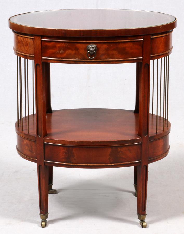 MAHOGANY OVAL TABLE, C. 1940, H 27", W 22", D 16": MAHOGANY OVAL TABLE, C. 1940, H 27", W 22", D 16"Tooled leather top, brass decorative rods. On wheels.