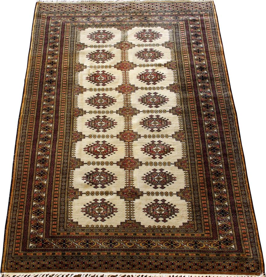 BOKHARA, HAND WOVEN WOOL RUG, W 4' 2", L 6' 5": BOKHARA, HAND WOVEN WOOL RUG, W 4' 2", L 6' 5" A hand woven Pakistani Bokhara wool rug. Having an ivory ground with rows of 'guls' in the central field with pinks, salmons, and yellows. Multiple borde