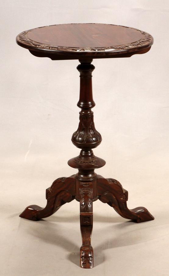 VICTORIAN CARVED WALNUT TEA TABLE: VICTORIAN CARVED WALNUT TEA TABLE, H 30" DIA 19.5" Having a round top with a carved edge and a carved shaft that tapers down to a three-footed base. The tabletop does not tilt.