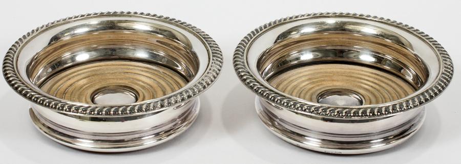 BARKER ELLIS SILVERPLATE & WOOD BOTTLE COASTERS: BARKER ELLIS, SILVERPLATE & WOOD WINE BOTTLE COASTERS, PAIR, DIA 5.7" Silverplate by Barker Ellis, England. Property of Robert Schweizer, Ann Arbor.