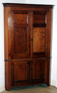 AMERICAN CHERRY CORNER CUPBOARD, CIRCA 1800, H: Two paneled doors above two paneled doors at the base, diamond-form key escutcheons, scalloped decorations centering the bracket feet, beaded detail at the cornice. One piece. Nice old original back