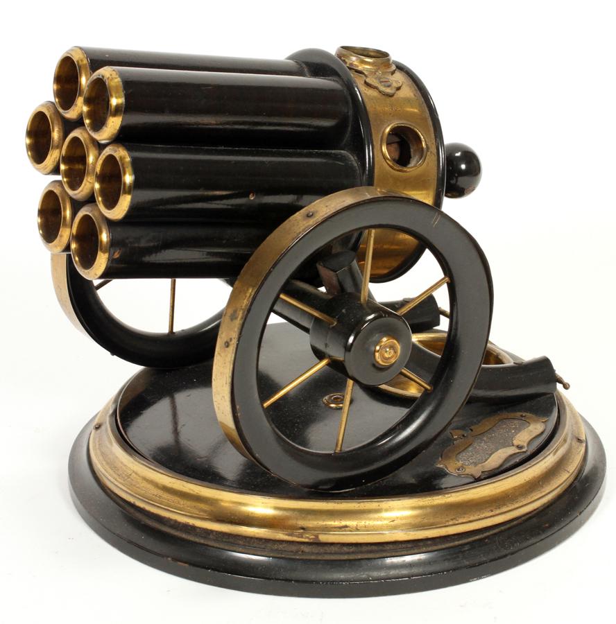 VICTORIAN CANNON COMPENDIUM CIGAR CUTTER, C1890: VICTORIAN, CANNON COMPENDIUM BRASS AND ENAMEL CIGAR CUTTER, C1890, H 6 1/2", W 7" Cigar cutter in the form of a multi-barreled cannon of brass and enamel mounted on a round base.