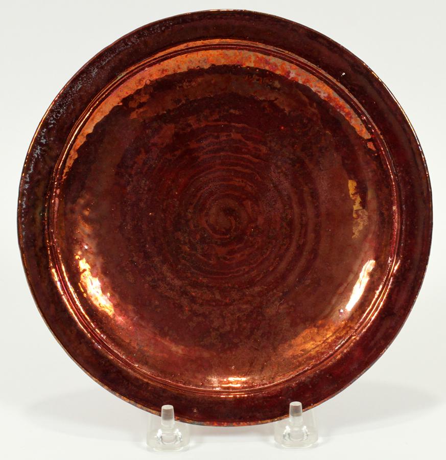 IRA & ELLA PETERS, POTTERY PLATE, 1976, DIA 7.25": IRA & ELLA PETERS, POTTERY PLATE, 1976, DIA 7.25"An Ira and Ella Peters signed Pewabic Pottery plate. Having a white clay composition and iridescent glaze boasting oxblood, copper and turquoise tones 