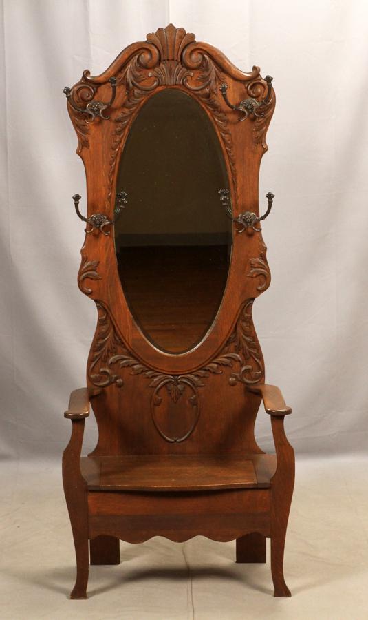 ANTIQUE OAK HALL TREE WITH MIRROR, C 1900, H 80": ANTIQUE OAK HALL TREE WITH MIRROR, C 1900, H 80", W 28", D 18" An oak hall tree with an oval bevel glass mirror set into an oak back panel with an applied carved acanthus-leaf motif and flanked by fou