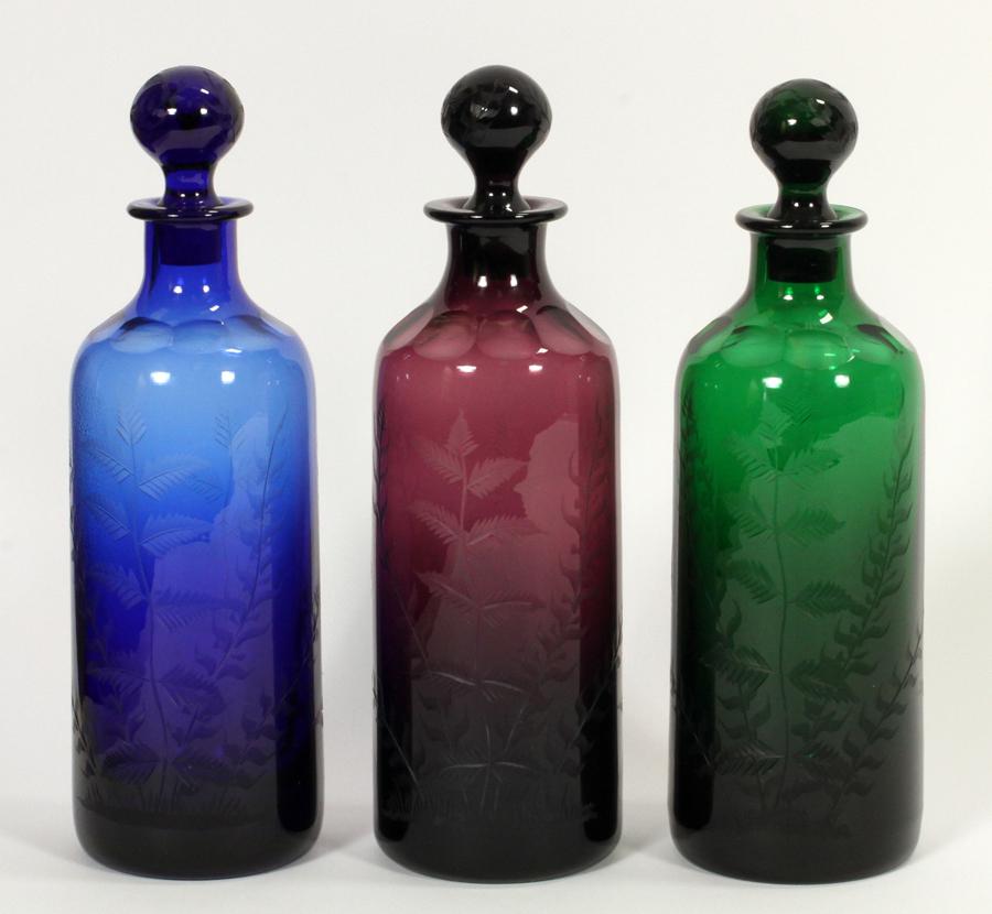WILLIAM YEOWARD COLORED CRYSTAL DECANTERS: WILLIAM YEOWARD (BRITISH) COLORED CRYSTAL DECANTERS, 3 PCS, H 12" A collection of William Yeoward colored crystal decanters. Offering jewel tones and etched fern motifs to the bodices. Signature brand