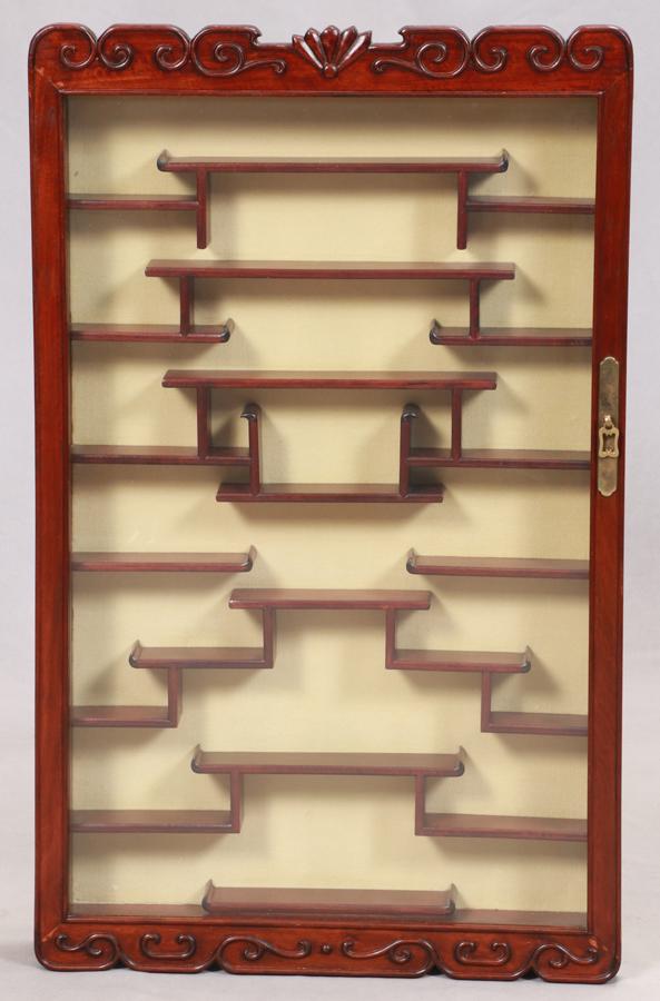 CHINESE TEAKWOOD NETSUKE WALL CURIO CABINET: CHINESE TEAKWOOD NETSUKE WALL CURIO CABINET H 34.5" W 21" .Single door inset with glass hinged to open to an arrangement of staggered shelves to highlight small collectibles.