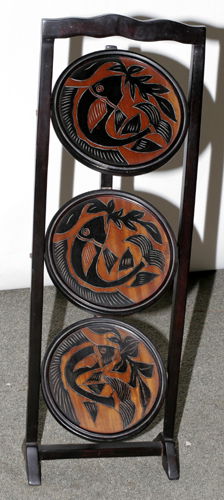 CARVED WOOD THREE-TIER COLLAPSIBLE MUFFIN STAND: CARVED WOOD THREE-TIER COLLAPSIBLE MUFFIN STAND, H 32", DIA 11"Fish design incised on shelves. Circa 1980.
