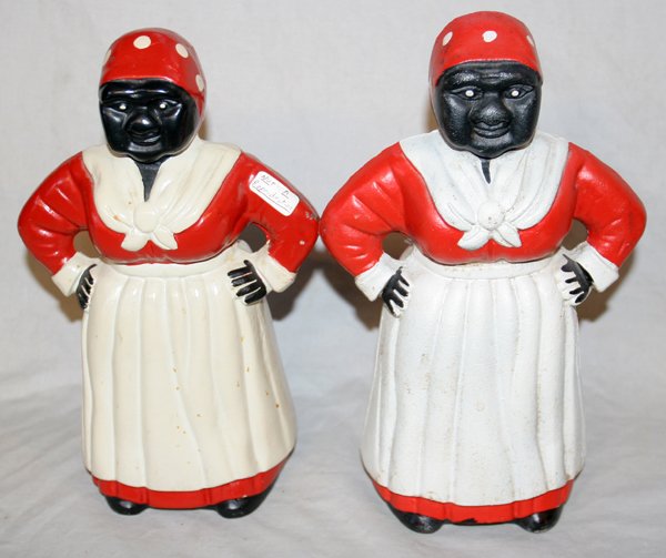 PAINTED CAST IRON 'MAMMY' BANKS, H 10 1/2": PAINTED CAST IRON 'MAMMY' BANKS, TWO, H 10 1/2" & 11":Each figure is shown with her hands on her hips and wearing a red dress, white apron and a red and white polkadot kerchief. No apparent marks.
