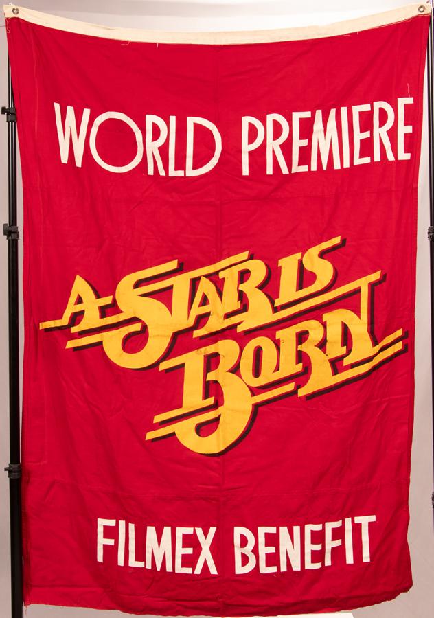 FILM PROP CANVAS BANNER, C. 1976: FILM PROP CANVAS BANNER, C. 1976, H 68", W 48", "A STAR IS BORN" A film prop canvas banner from Frank Pierson's 1976 film, "A Star Is Born." Printed on red canvas, "World Premiere 'A Star Is Born' Fil