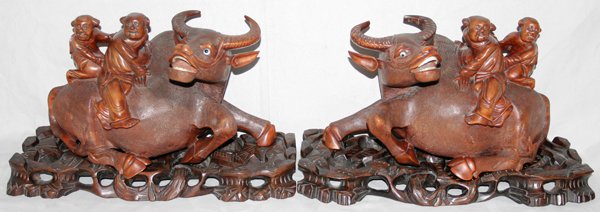 CHINESE CARVED WOOD SCULPTURES, PAIR, H 8": CHINESE CARVED WOOD SCULPTURES, PAIR, H 8", L 14":Depicting oxen with figures riding them. On a carved wood base. From the Estate of Robert D. Ellinger, Grand Rapids, MI.