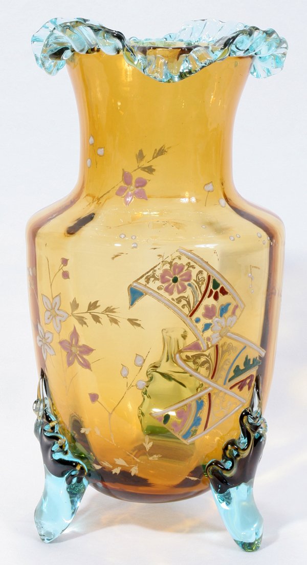 STEVENS & WILLIAMS ENAMELED VASE, H 13": STEVENS & WILLIAMS ENAMELED VASE, H 13":An amber glass vase with subtle vertical striations, having a light blue glass ruffled rim and three applied feet, enameled floral motifs in pink, white and blu