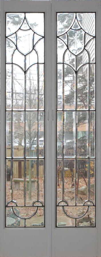 BEVELED CLEAR GLASS DOOR PANELS PAIR H 78.25" W 15.25": BEVELED CLEAR GLASS DOOR PANELS PAIR H 78.25" W 15.25" Glass is encased in white and brown painted wood frames.Provenance: Estate of Jack Faxon, Birmingham, MI. Michigan Senator and creator of the Mic