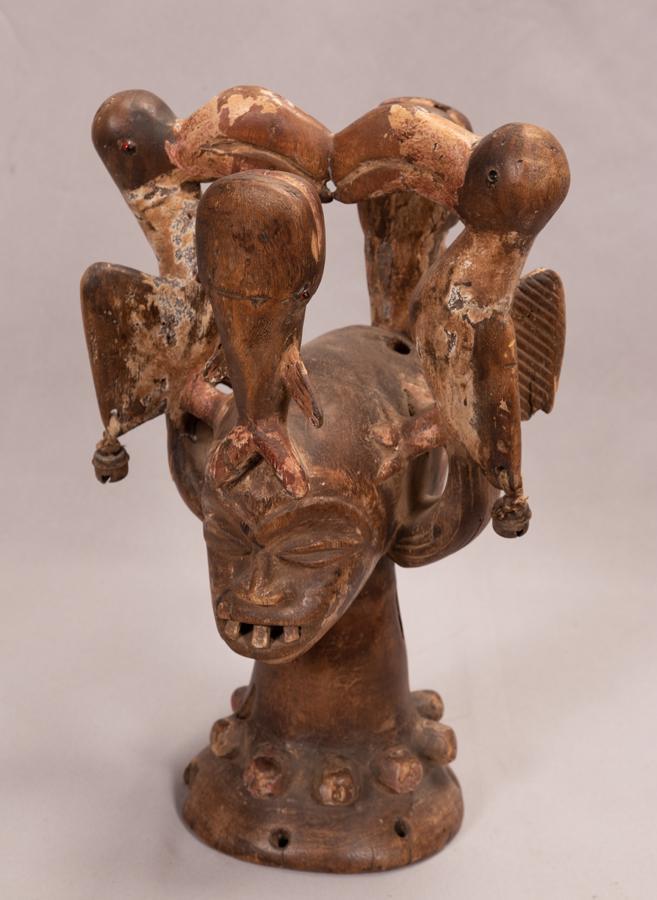 EKOI, NIGERIA, AFRICAN, HEADRESS WITH BIRDS H 17" W: EKOI, NIGERIA, AFRICAN, HEADRESS WITH BIRDS H 17" W 10.5" WOOD, METAL, BEAD, PIGMENT, BELLS D 10" Multi faced, with three pronounced teeth, and elephants atop their heads, the birds with bells on thei