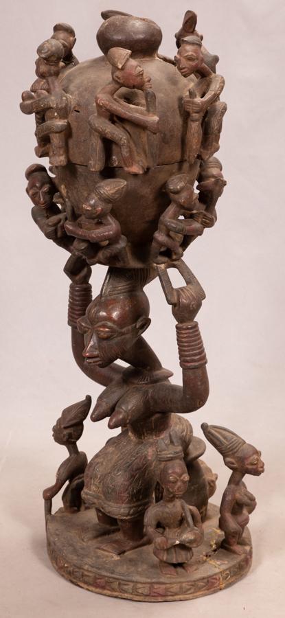 YORUBA (IFE TRADITION) AFRICAN PATINATED WOOD ALTAR: YORUBA (IFE TRADITION) AFRICAN PATINATED WOOD ALTAR BOWL H 35.75" DIA 12" Having fully carved sculptural base with semi nude female figure seated on a stool supporting ornate gourd formed vessel adorn