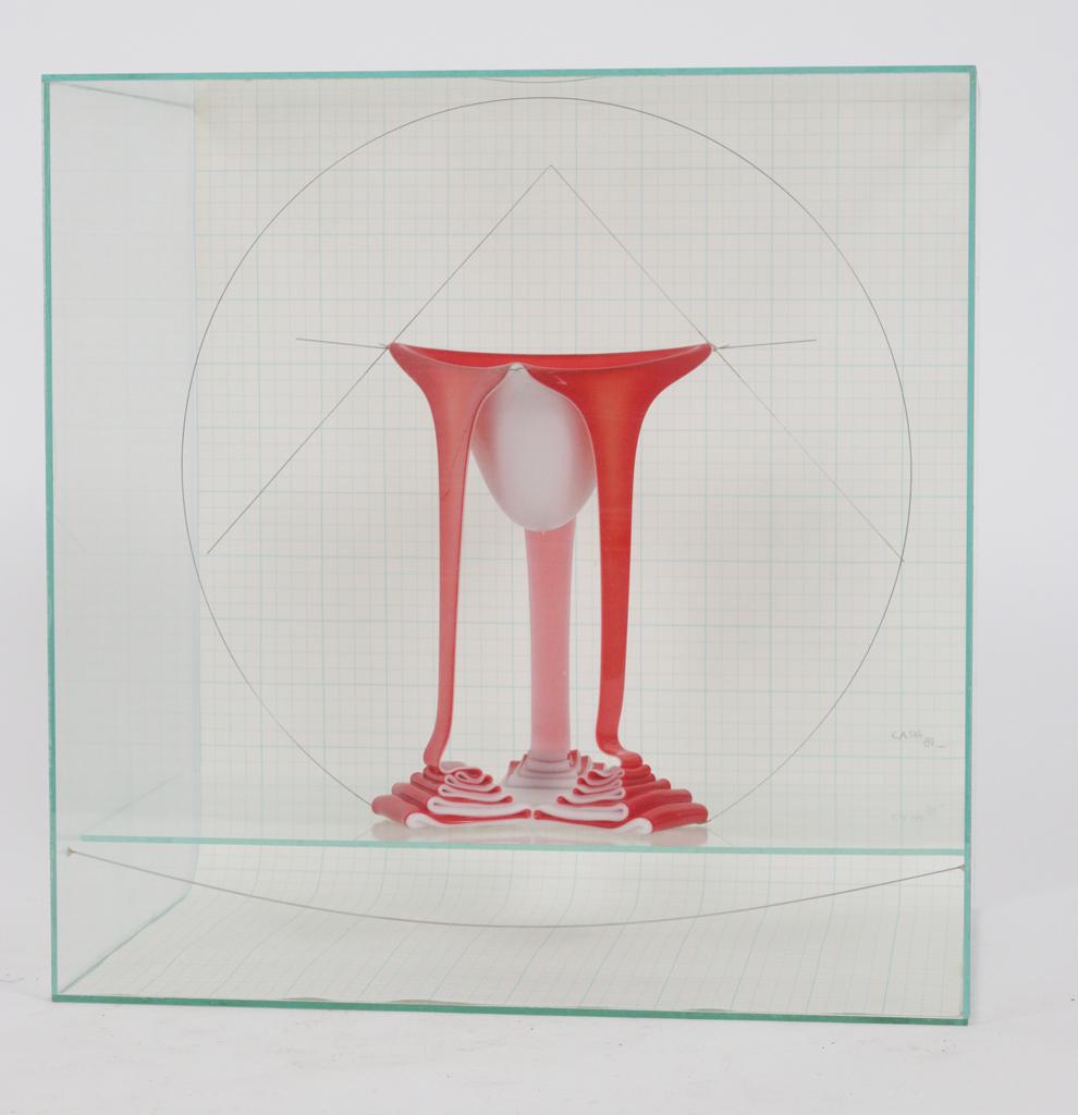 SYDNEY CASH (AMERICAN B. 1941) GLASS SCULPTURE: SYDNEY CASH (AMERICAN B. 1941) GLASS SCULPTURE SUSPENDED ON WIRE, 1981, H 11" W 12" DIA 6" Magenta and milk glass fusion, in a glass case. Signed and dated (81) on the graph paper background. Estate o