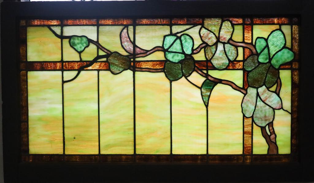 LEADED SLAG GLASS WINDOW PANE 1910-1930 H 27, W 47": LEADED SLAG GLASS WINDOW PANE 1910-1930 H 27, W 47" GRAPE VINES AND LEAVES ON TRELLIS Green to yellow to brown background panels with a brown border and trellis motif. Encased in painted wood frame. O