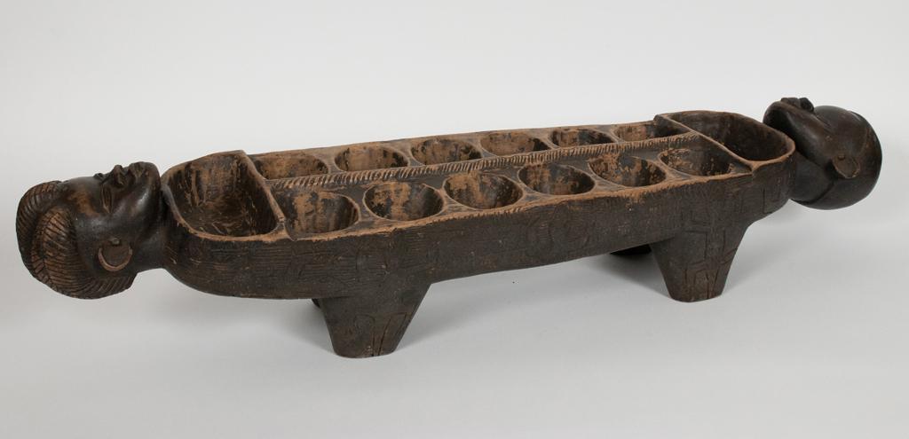 YORUBA, NIGERIA, AFRICAN CARVED WOOD MANCALA PLAYING: YORUBA, NIGERIA, AFRICAN CARVED WOOD MANCALA PLAYING BOARD H 9.5" W 7.5" L 39.5" Estate of Jack Faxon, Birmingham, MI. Michigan Senator and creator of the Michigan Council for the Arts.