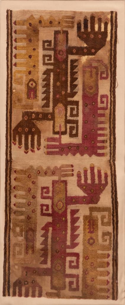 PRE-COLUMBIAN EMBROIDERED CLOTH H 25" W 10": PRE-COLUMBIAN EMBROIDERED CLOTH H 25" W 10" Depicts stylized animals rendered in red and yellow and brown tones, presented in an acrylic frame that measures H 34" W 18" D 2.5"From the estate of Jack F