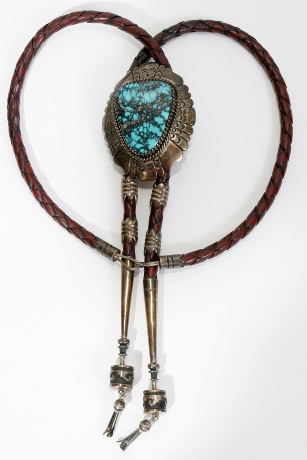 TOMMY SINGER, SILVER/TURQUOISE/LEATHER BOLO TIE: TOMMY SINGER, NAVAJO HAND-CRAFTED SILVER, TURQUOISE & LEATHER BOLO TIE:Leather necklace with handmade silver accents and tips featuring a large turquoise cabochon slide. Cabochon L. approx. 3", W. 2 1