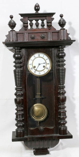 GERMAN MAHOGANY WALL CLOCK, C. 1880, H 36",: GERMAN MAHOGANY WALL CLOCK, C. 1880, H 36", W 17":Enamel dial, roman numerals, key wind, spring movement, brass pendulum. Spool turnings decorate case. Key in consignment file. No finials on top.
