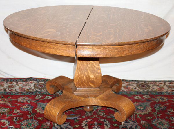 AMERICAN OAK DINING TABLE, C. 1910, H 29",: AMERICAN OAK DINING TABLE, C. 1910, H 29", DIA 48", WITH FOUR LEAVES:A round top raised on a pillar and scroll style base. Each leaf 12" wide.
