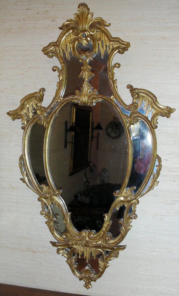 CARVED WOOD MIRROR, GILT, 48" X 29": GEORGIAN STYLE CARVED WOOD MIRROR, GILT, 48" X 29":Shield shape, flourish at crest. Quality hand carved frame. Circa 1950. Italian. From the Estate of Waldo A. Schaefer, M. D. Port Huron, Mi.