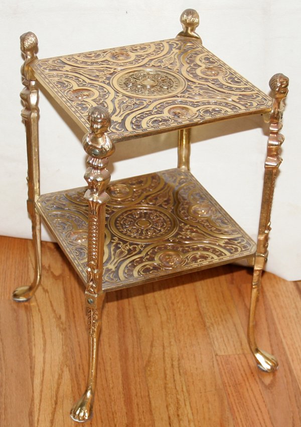 BRASS TWO TIER STAND, H 19", W 12": BRASS TWO TIER STAND, H 19", W 12":Two tier. Brass plate over metal. Paw feet and lady head terminals. From the Collection of Alfred S. Warren. Good condition.