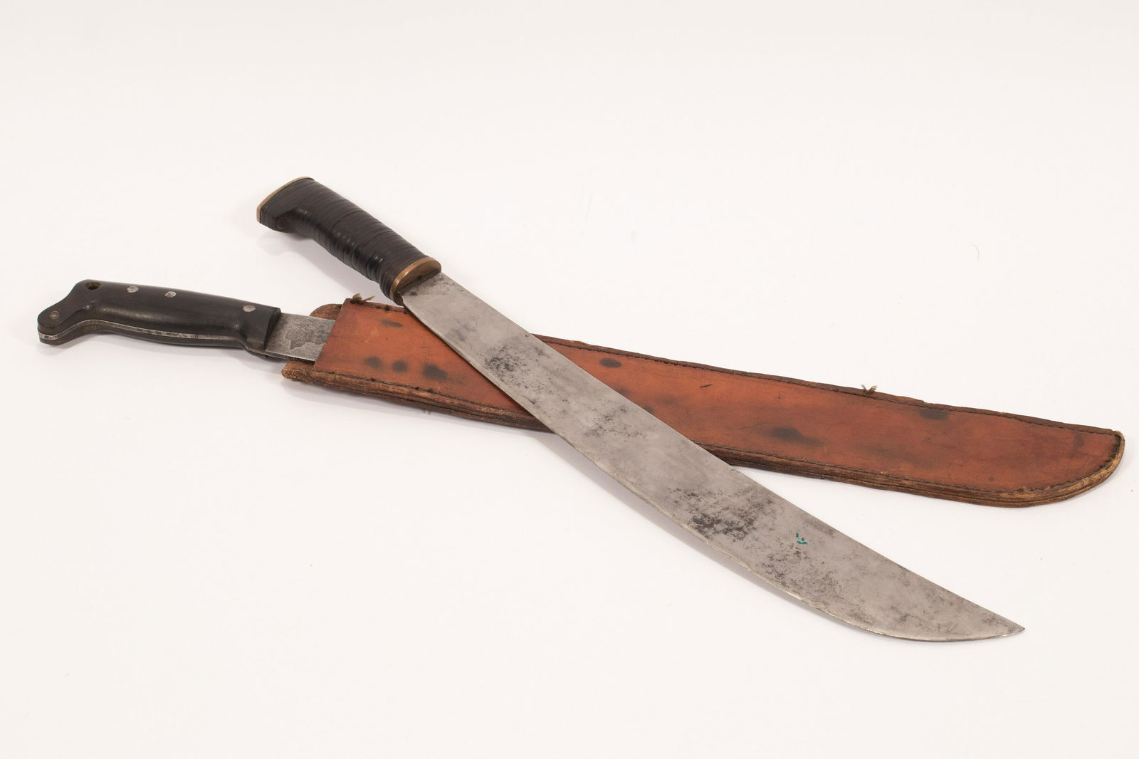 WWII ERA LEGITIMUS COLLINS & CO. MACHETES, C. 1945, TWO: WWII ERA LEGITIMUS COLLINS & CO. MACHETES, C. 1945, TWO PCS., L 18" AND 17" BLADES One machete (18" blade) marked "US Legitimus Collins & Co 1945" under a crown with arm holding hammer, looks to be an