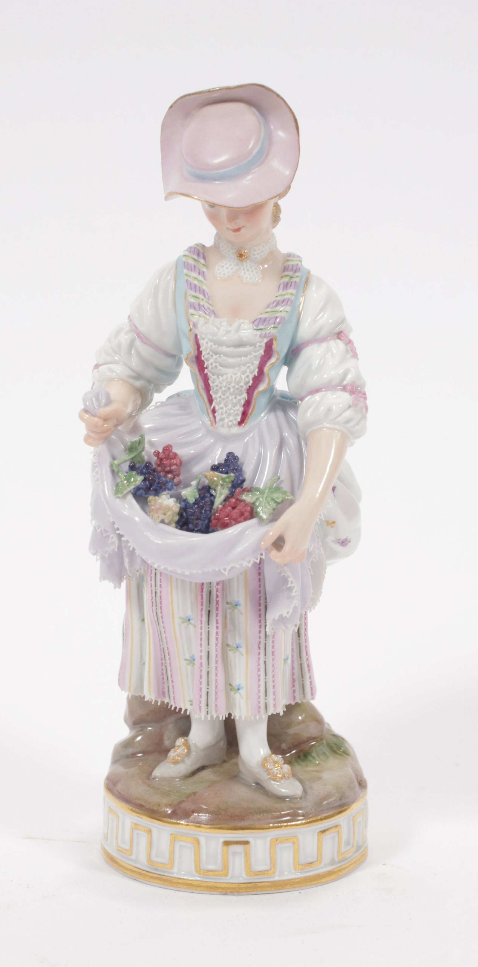 MEISSEN (CO.) (GERMAN, ESTABLISHED 1710) PORCELAIN: MEISSEN (CO.) (GERMAN, ESTABLISHED 1710) PORCELAIN FEMALE GATHERING FRUIT H 7" W 2.3" Incised F34, impressed 127, enameled 11 and the crossed swords scored through. Modeled as a female, her hat tipped
