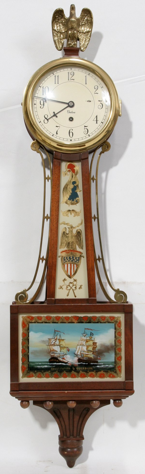 CHELSEA MAHOGANY BANJO CLOCK, MODERN, H 32": CHELSEA MAHOGANY BANJO CLOCK, MODERN, H 32":Reproduction banjo clock with perched eagle finial, an eglomaise panel at the base depicts the ships "Constitution & Guerriere". No key.