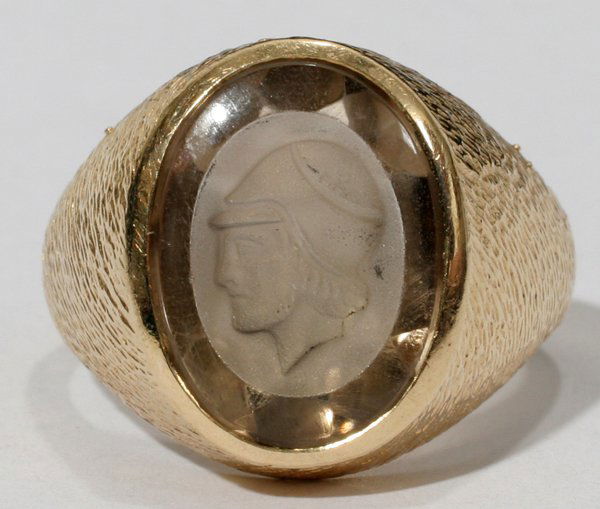 GENTS 14KT. Y/GOLD & SMOKY QUARTZ INTAGLIO RING: GENTS 14KT. YELLOW GOLD AND SMOKY QUARTZ INTAGLIO RING:The domed ring is set vertically with a 16.80 X 12.25mm oval smoky quartz intaglio (featuring a warrior head in profile) which is medium light, b