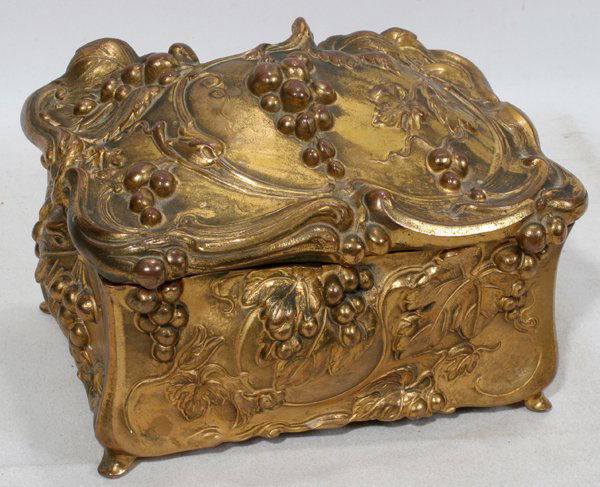 ART NOUVEAU GILT METAL DRESSER BOX, H 5", L 7": ART NOUVEAU GILT METAL DRESSER BOX, H 5", L 7":Rectangular shape with raised grape bunch and leaf motif at the cover and all sides, marked "J.B. Trademark Signifies the Best" at the underside. Early 2