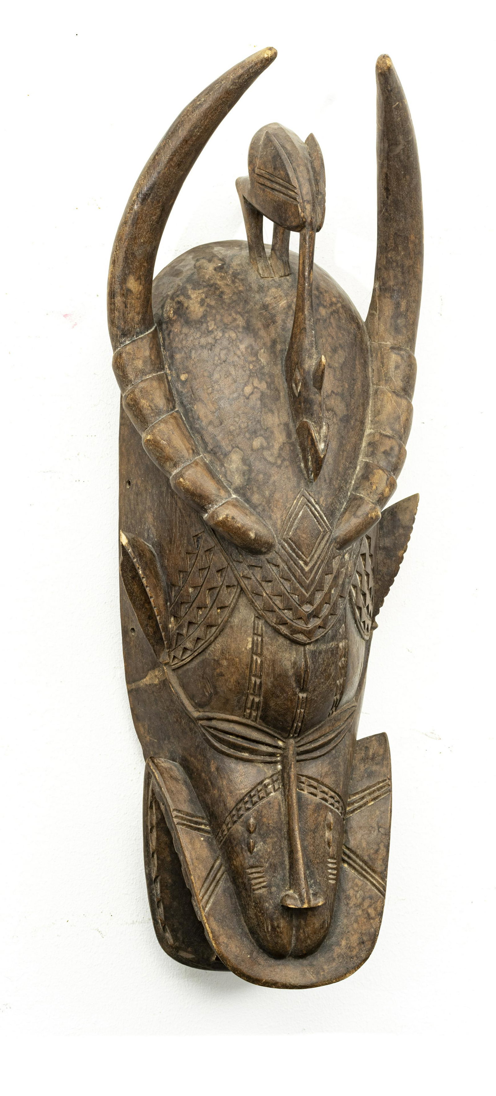 HORNED AFRICAN BAULE TRIBE CARVED WOOD MASK: HORNED AFRICAN BAULE TRIBE CARVED WOOD MASK H 26" W 10" Warrior's mask. Extending horns, bird crest, slit eyes, "alligator" mouth. Ivory Coast. From an Ann Arbor collector.