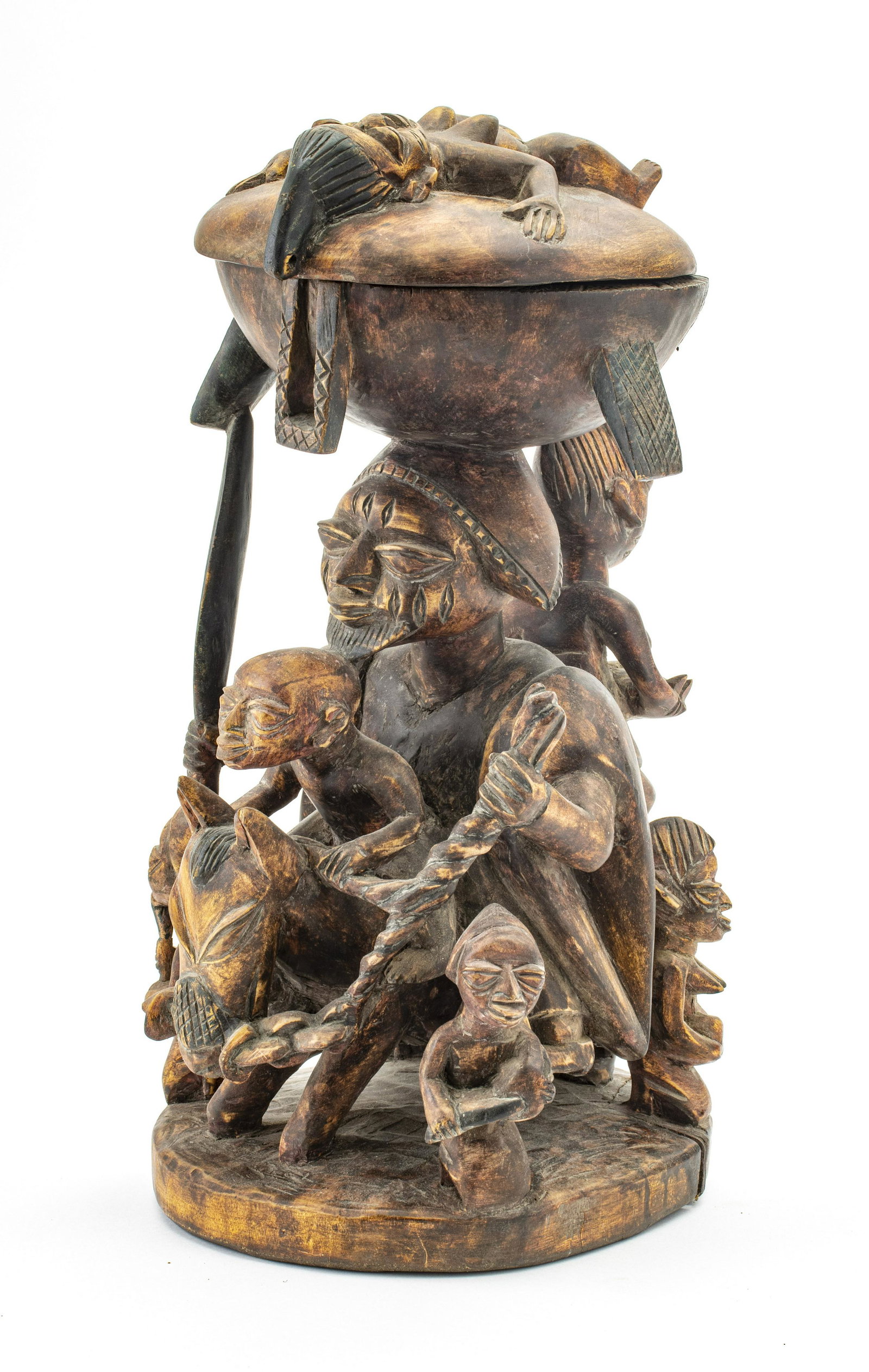 AFRICAN YORUBA AFRICAN, YORUBA DIVINATION BOWL: AFRICAN YORUBA AFRICAN, YORUBA DIVINATION BOWL 20TH C. H 18" D 10" Central large carved warrior with spear riding a burro surrounded by five attendants. Offering dish has loose cover with effigy. Prop