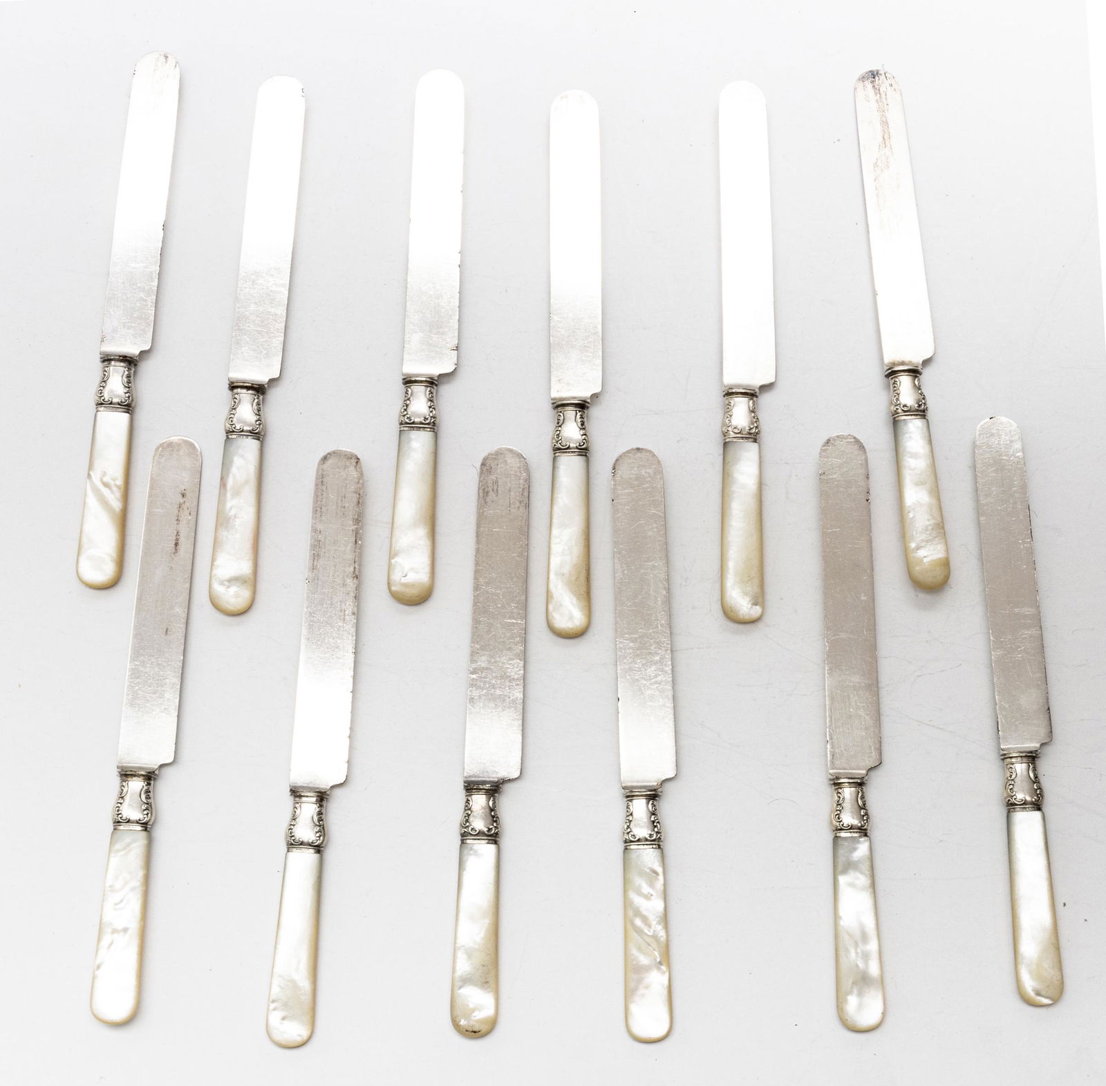 MOTHER OF PEARL HANDLE DINNER KNIVES, SET OF 12: MOTHER OF PEARL HANDLE DINNER KNIVES, SET OF 12, CIRCA 1880 L 9" Bands are sterling. Blades are silver plate. Landers Frary & Clark, Aetna. From a Dakota Circle, Bloomfield Hills collector.