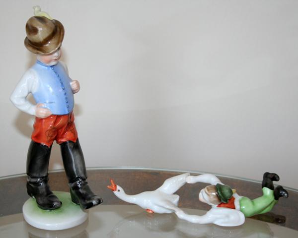 HEREND, PORCELAIN FIGURINES OF BOYS, 20TH C,: HEREND, PORCELAIN FIGURINES OF BOYS, 20TH C, 2 PCS., H 7" & 8":one depicts young boy holding a goose by the wings and other of a boy with high black boots and tilted hat;