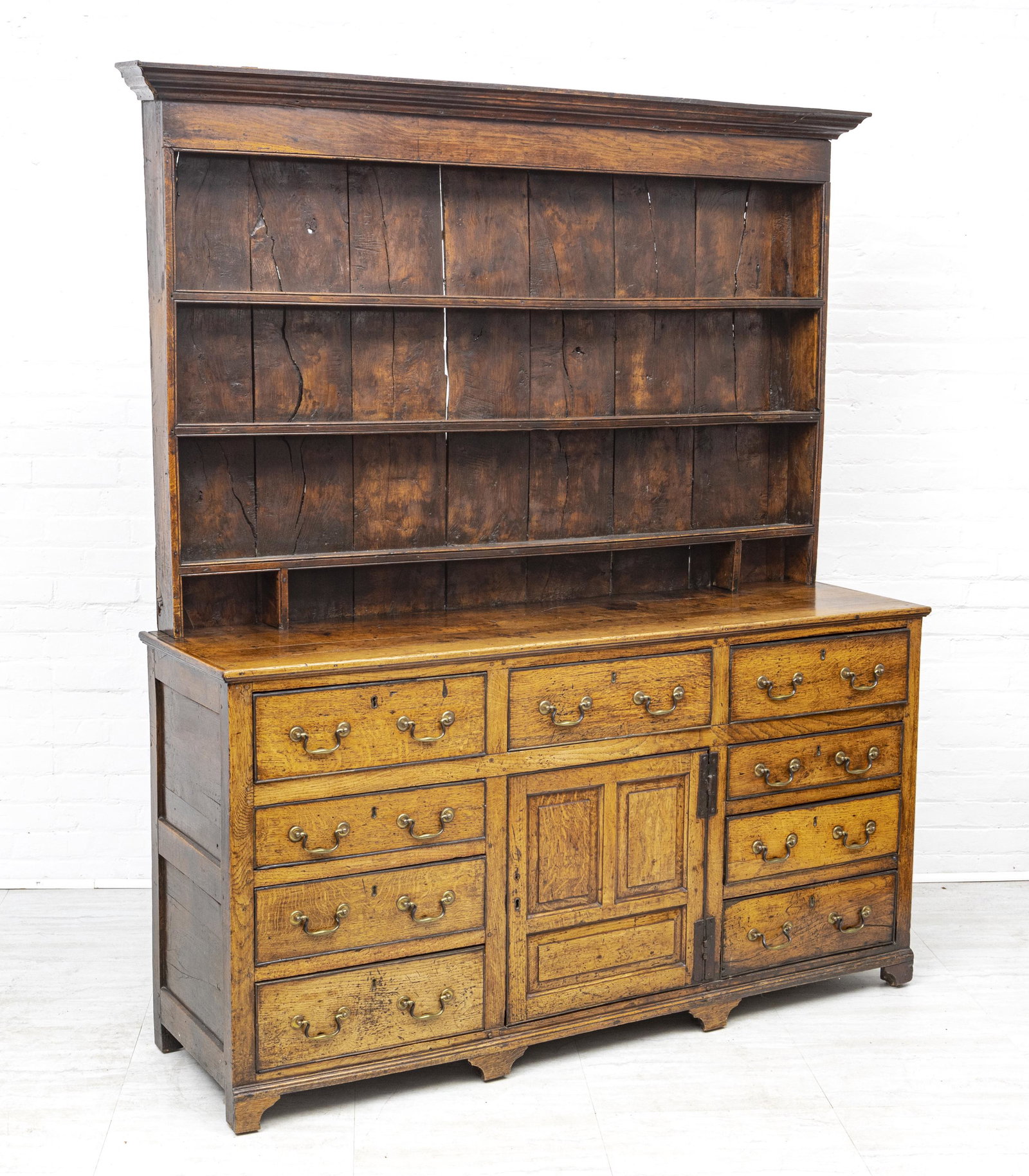 GEORGE III WELSH OAK DRESSER, 18TH.C. H 6'2" W 5'6" L: GEORGE III WELSH OAK DRESSER, 18TH.C. H 6'2" W 5'6" L 1'7" In two sections. Upper section with open shelves and molded cornice. . Base fitted with one cabinet and nine drawers. Made in the United King